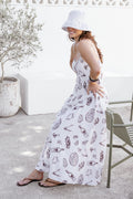 Woman in a white dress with food print standing outdoors.