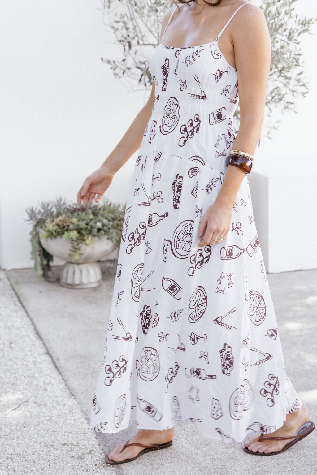 Woman wearing a white dress with red patterns in an outdoor setting
