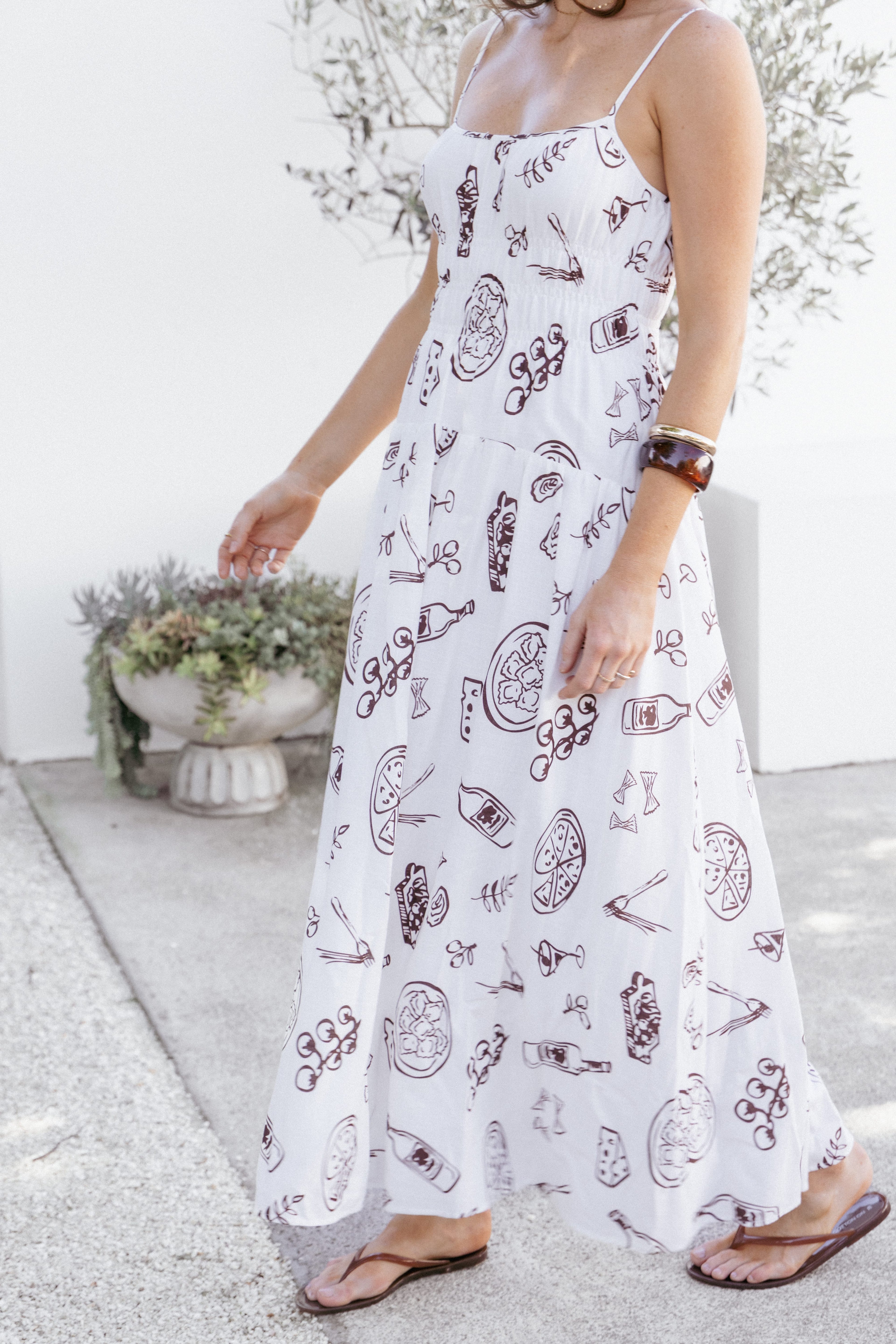 Woman wearing a white dress with red patterns in an outdoor setting