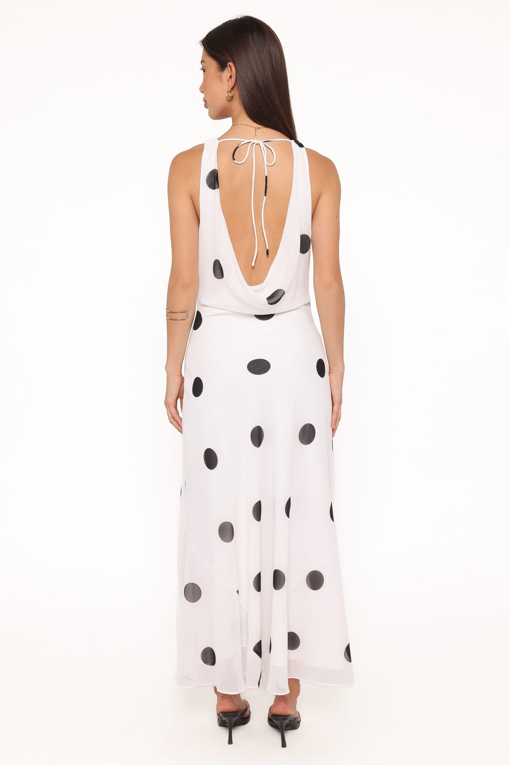 Woman wearing a white dress with black polka dots on a white background