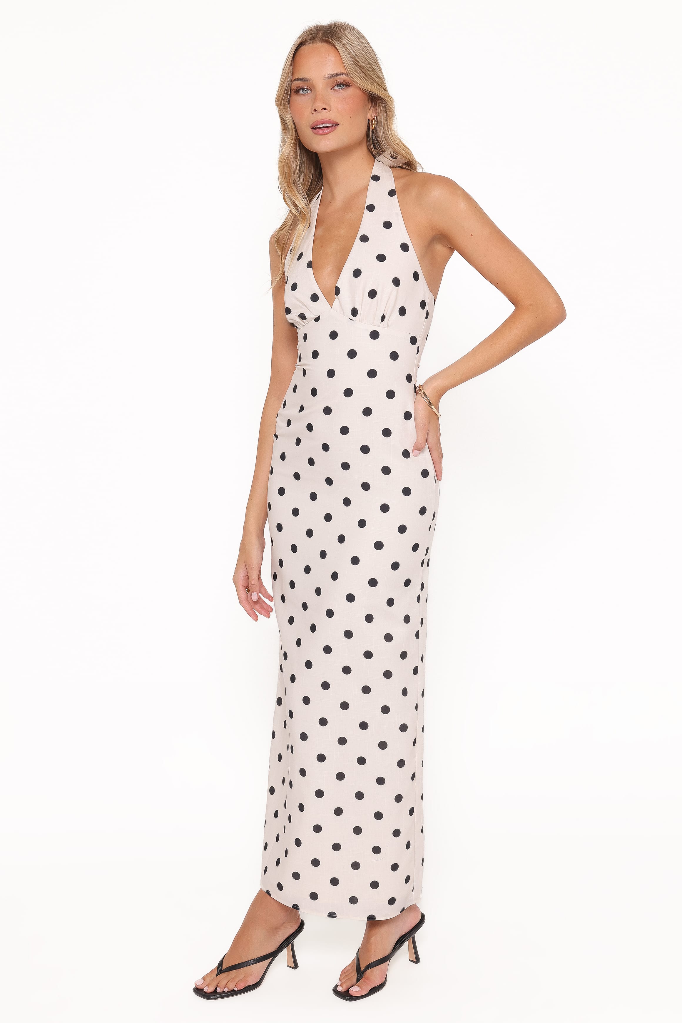 Woman wearing a polka dot halter neck dress on a white background