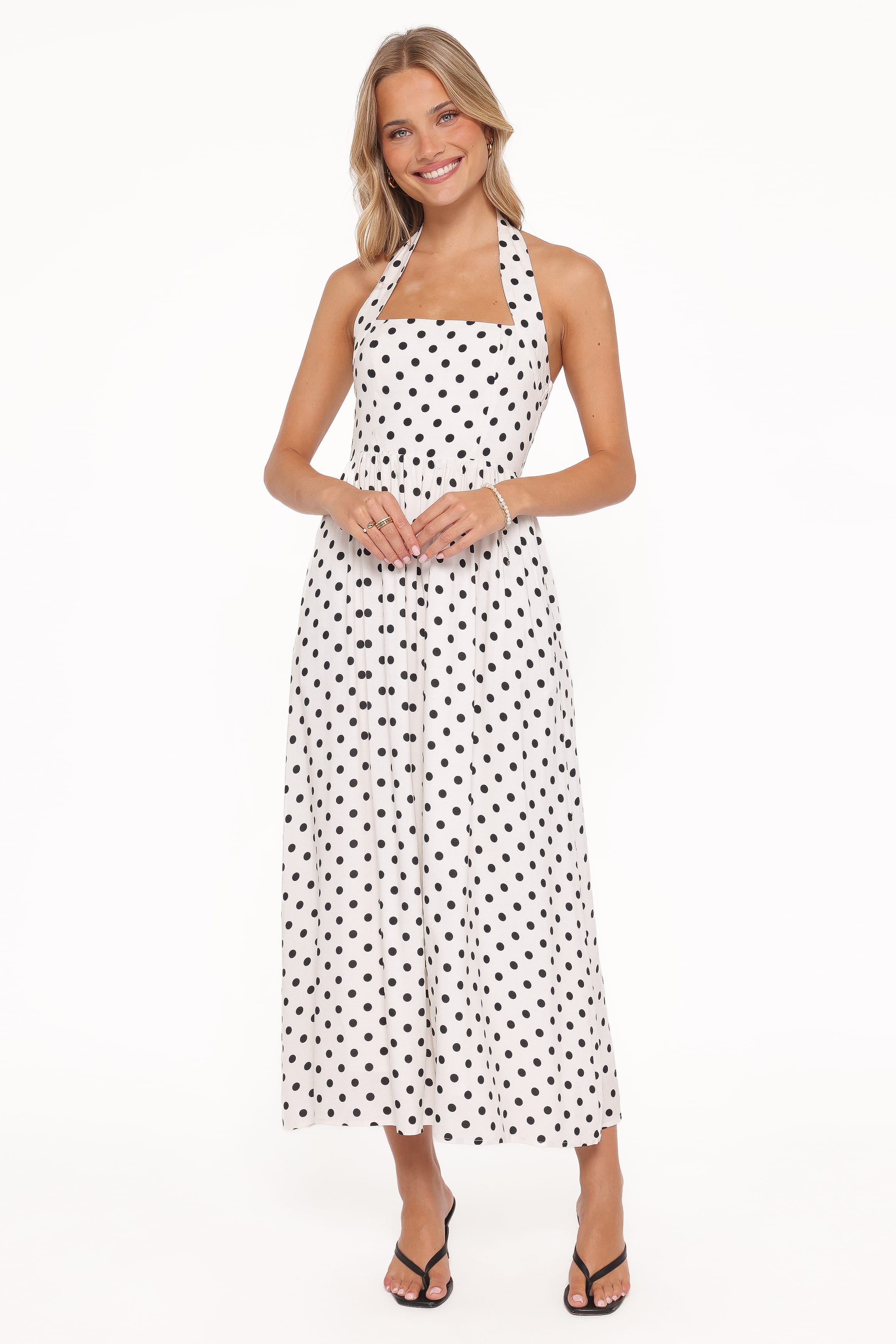 Woman wearing a white dress with black polka dots on a white background