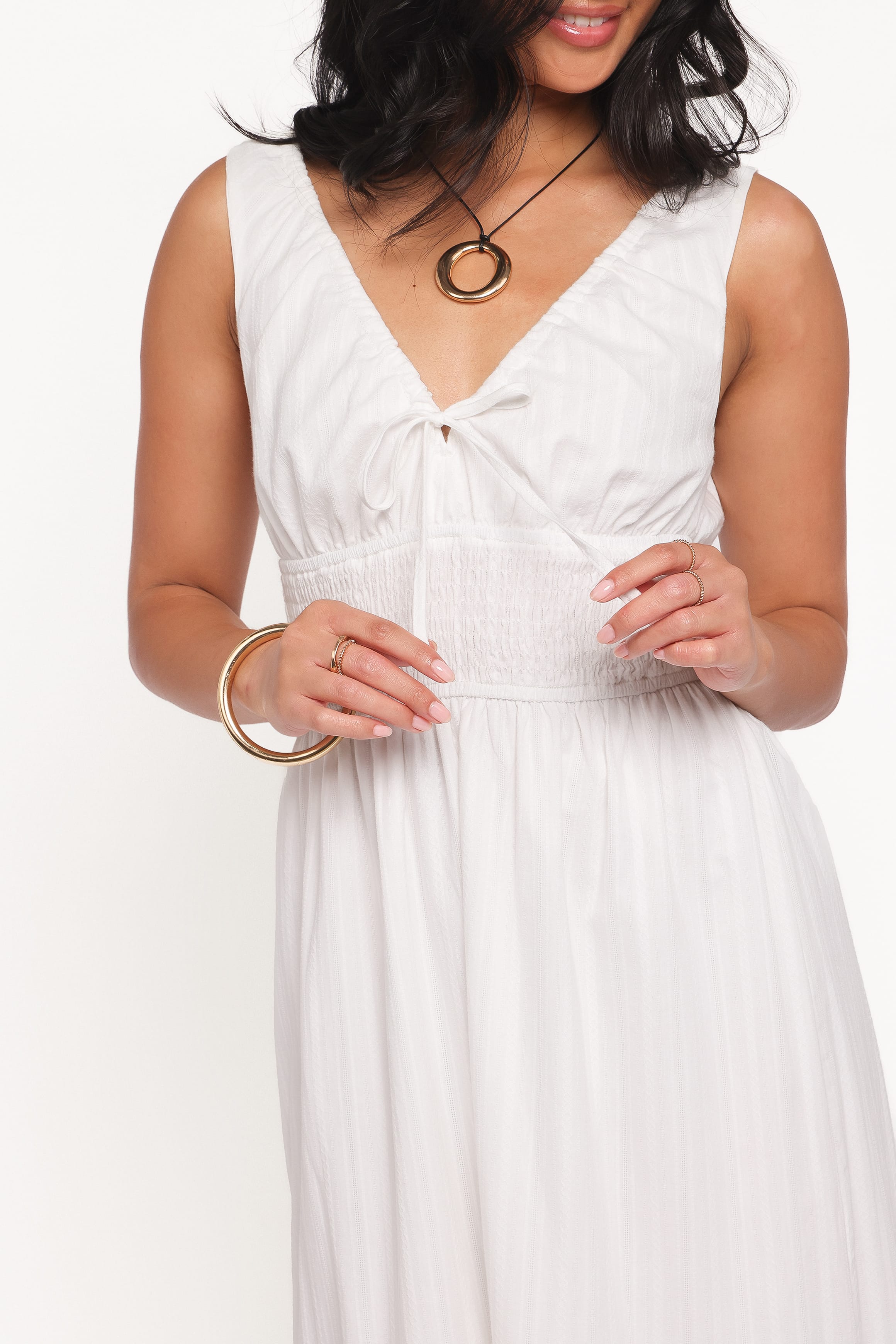Woman wearing a white dress with gold jewelry on a white background