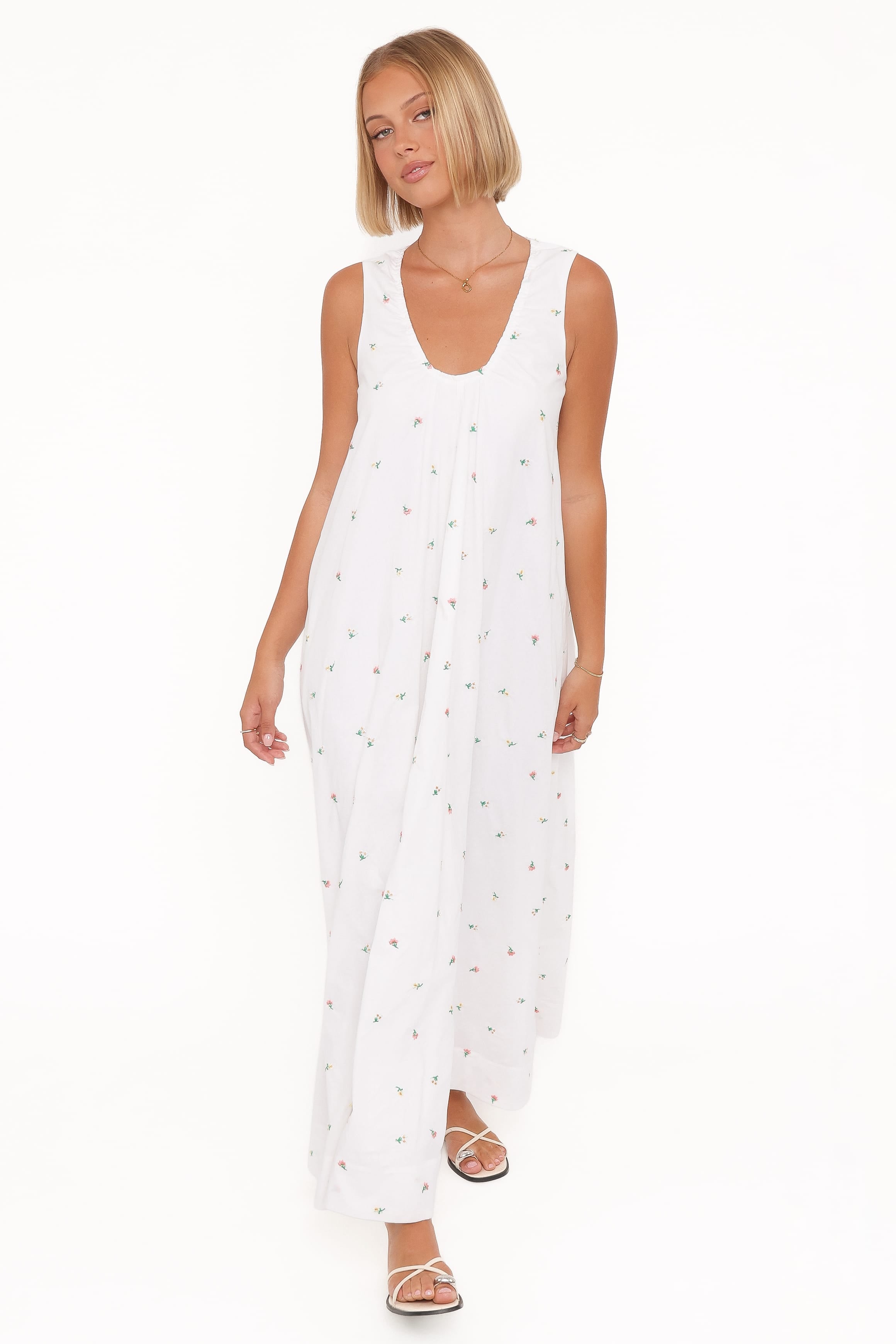 Woman wearing a white sleeveless dress with a subtle pattern on a white background