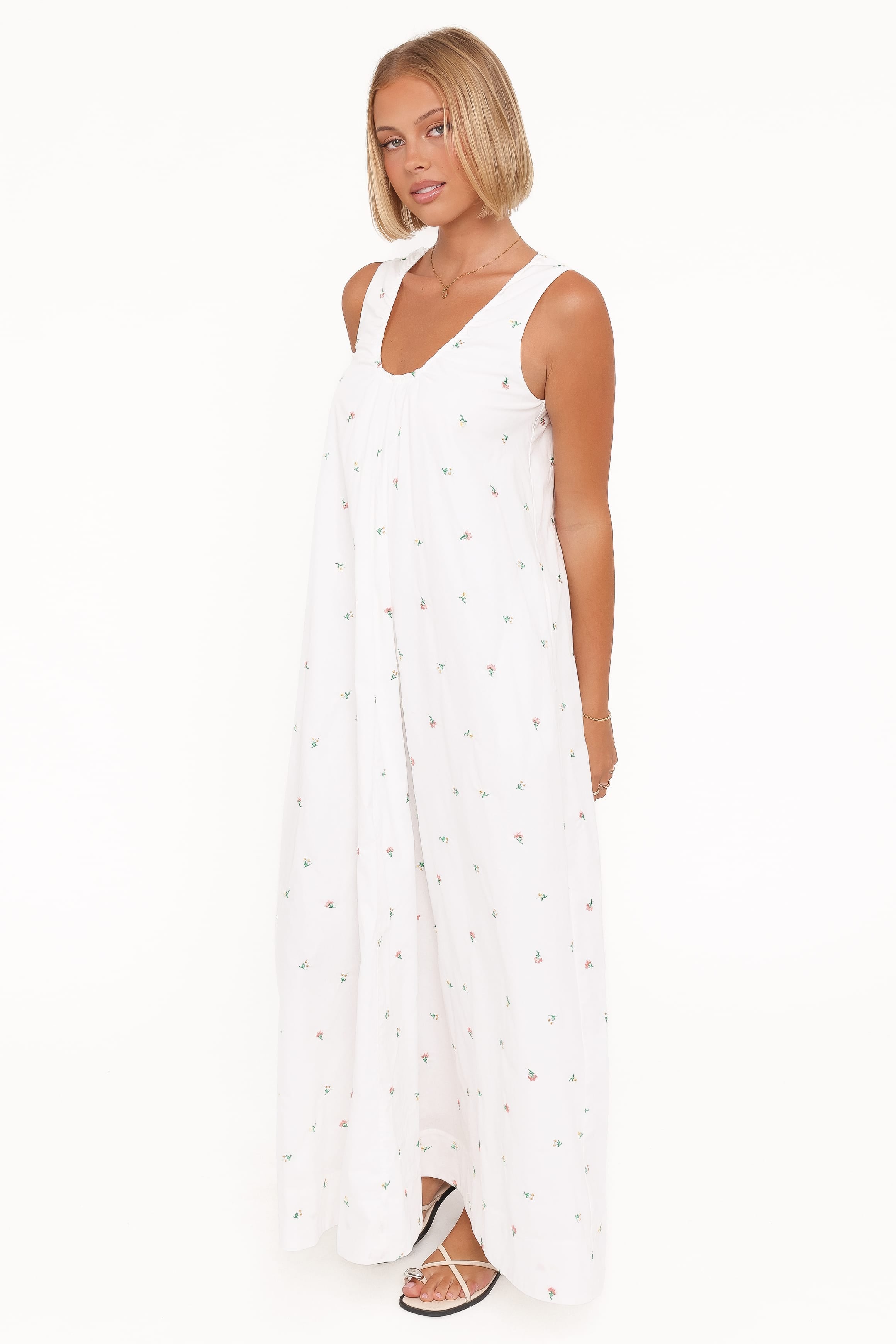 Woman wearing a white sleeveless dress with small patterns on a white background