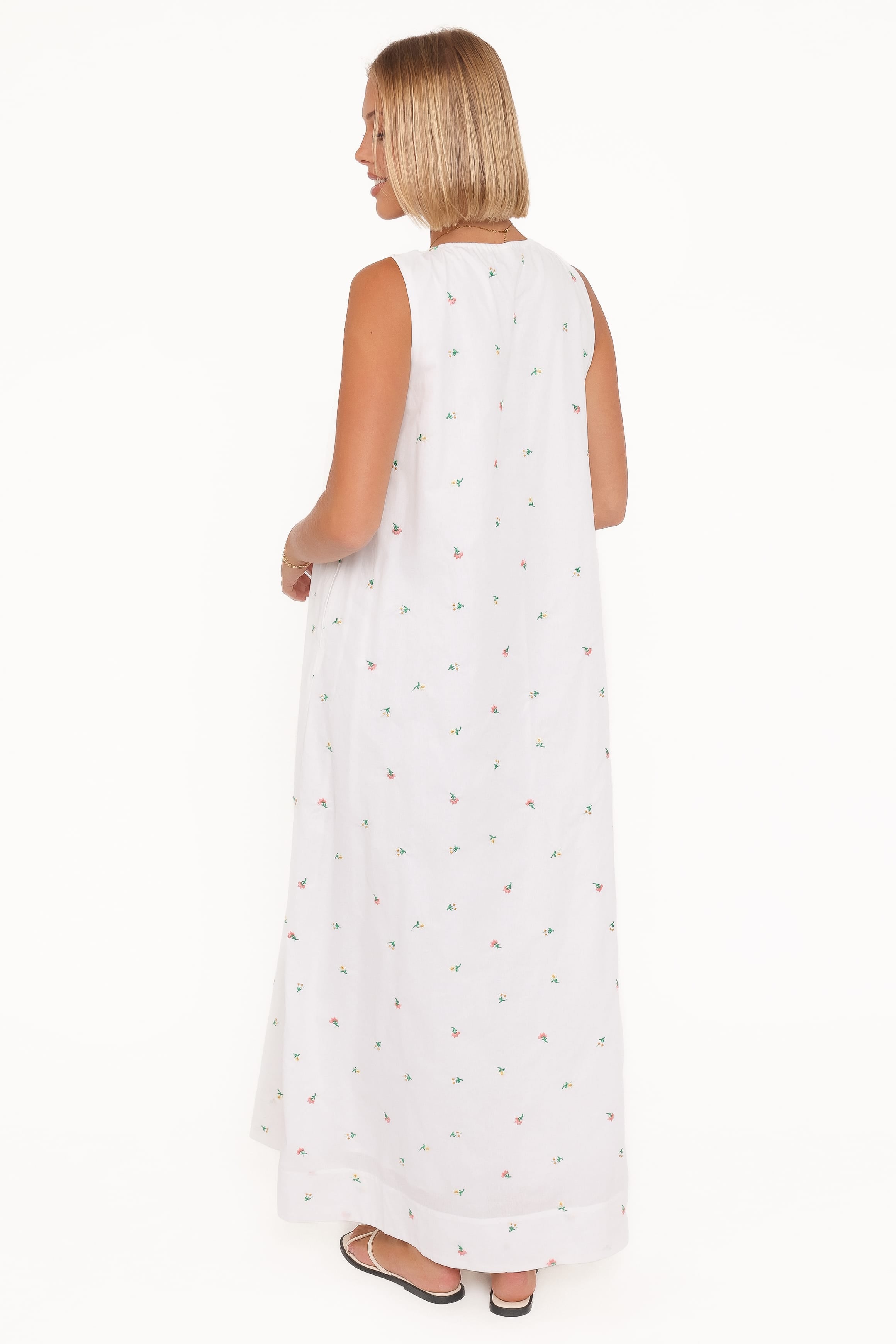 Woman wearing a white sleeveless dress with small patterns on a white background