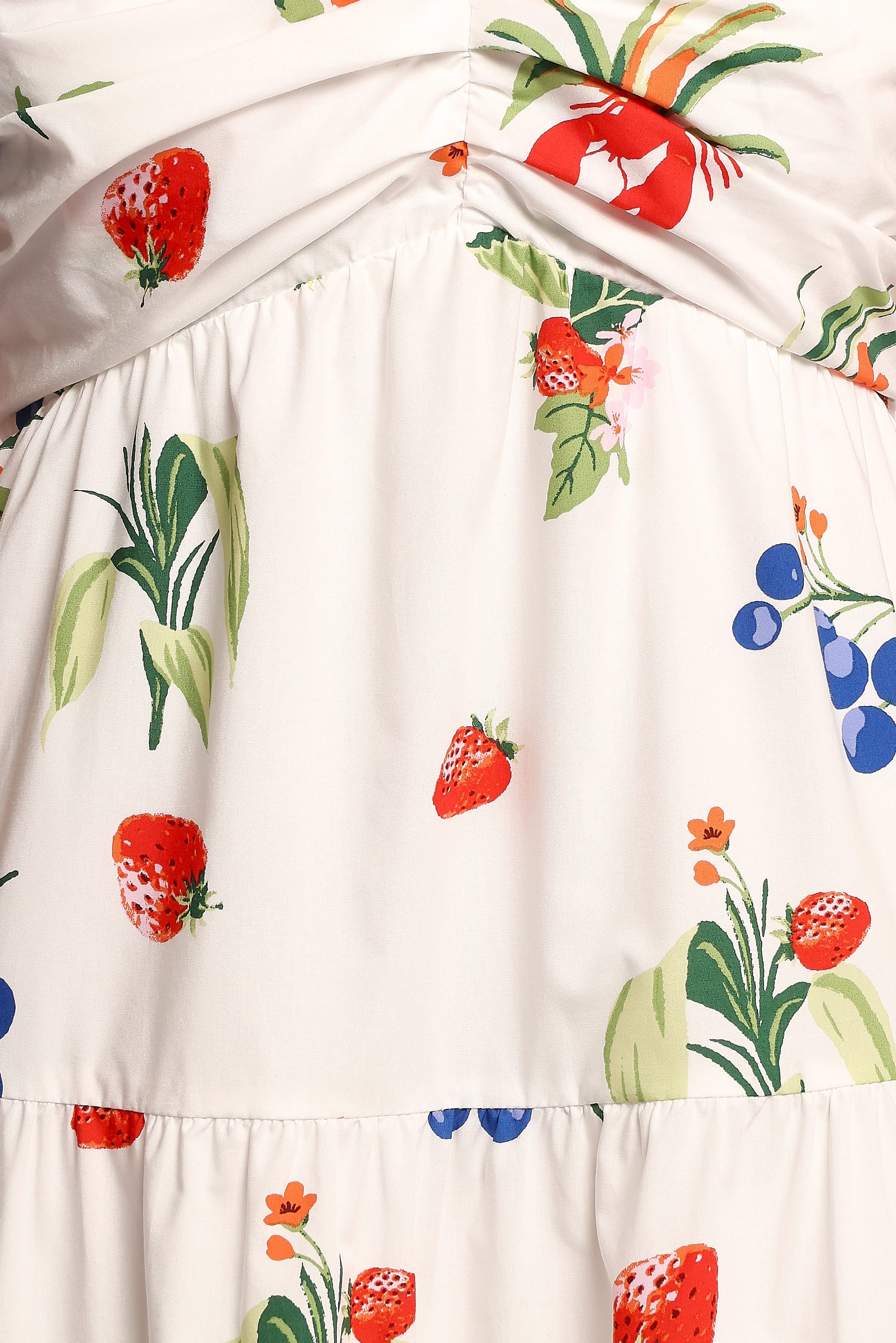 Close-up of a dress with colorful fruit and plant pattern on a white background