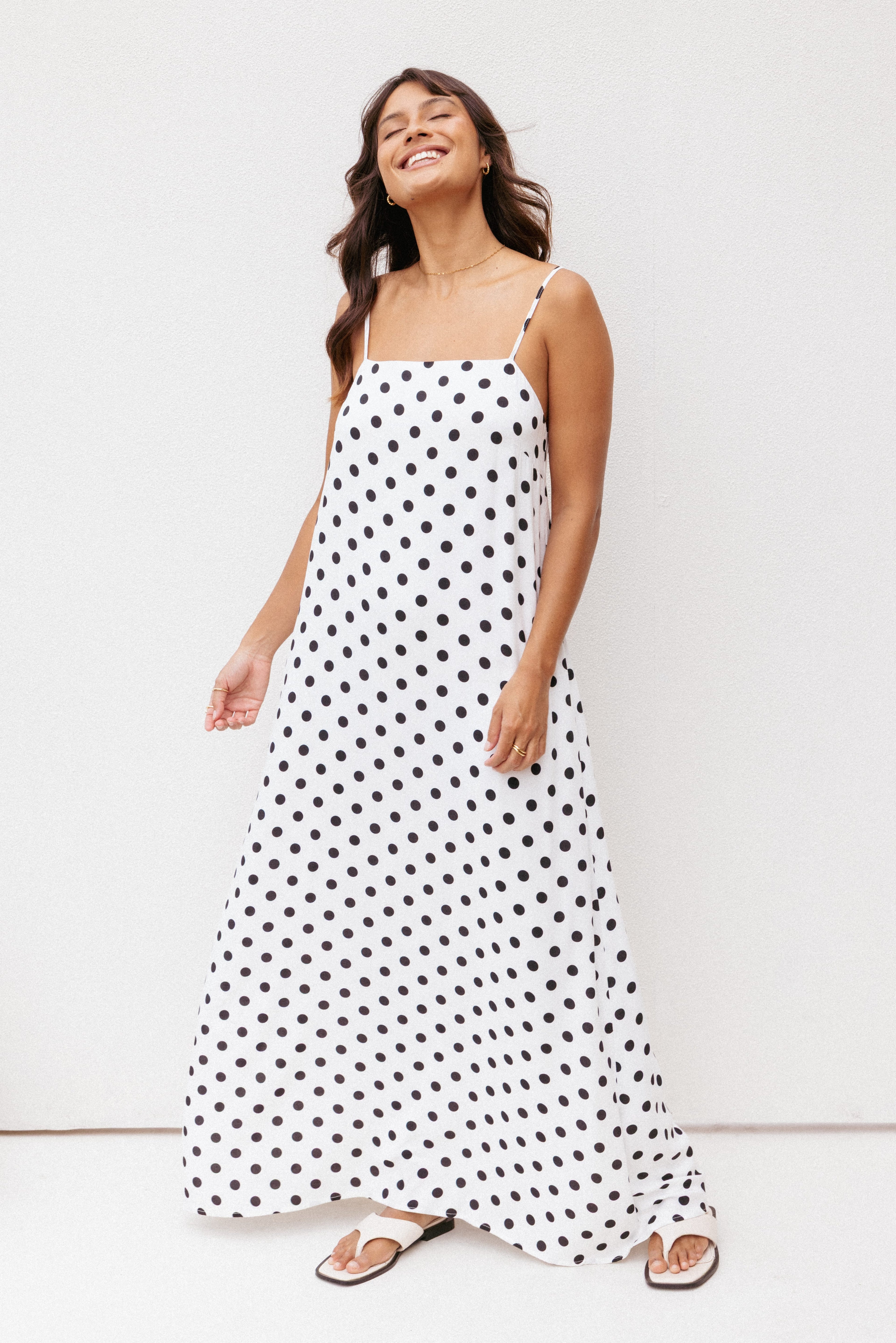 Woman wearing a black and white polka dot dress against a white background