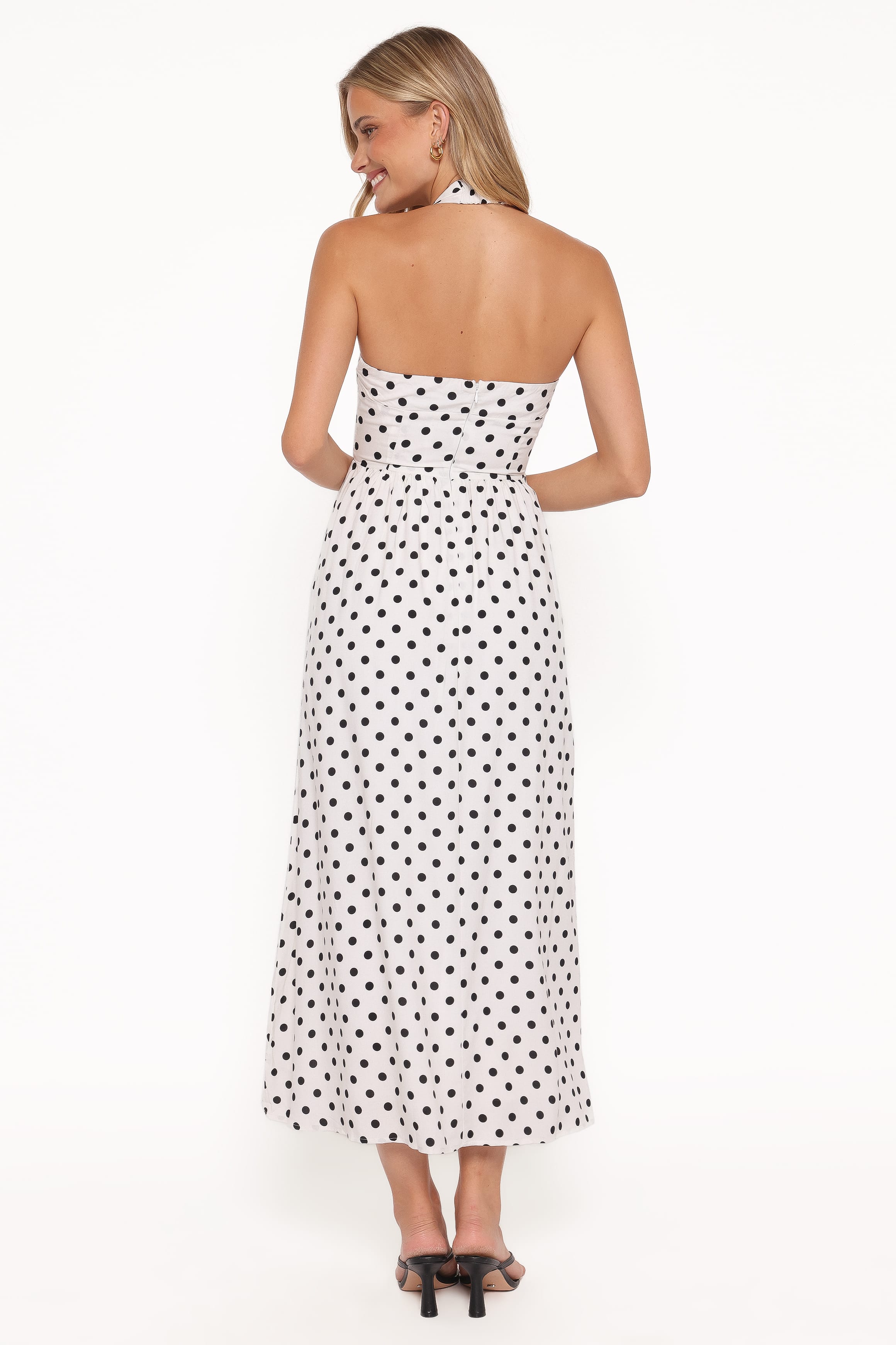 Woman wearing a strapless polka dot dress on a white background